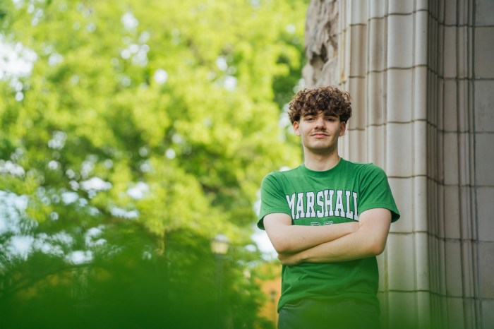 Mark Hysell wears a Marshall t-shirt and stands with his arms crossed in front of a stone building.