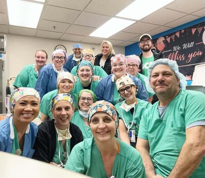 Nathan Welch with a large group of coworkers in a break room, everyone in scrubs