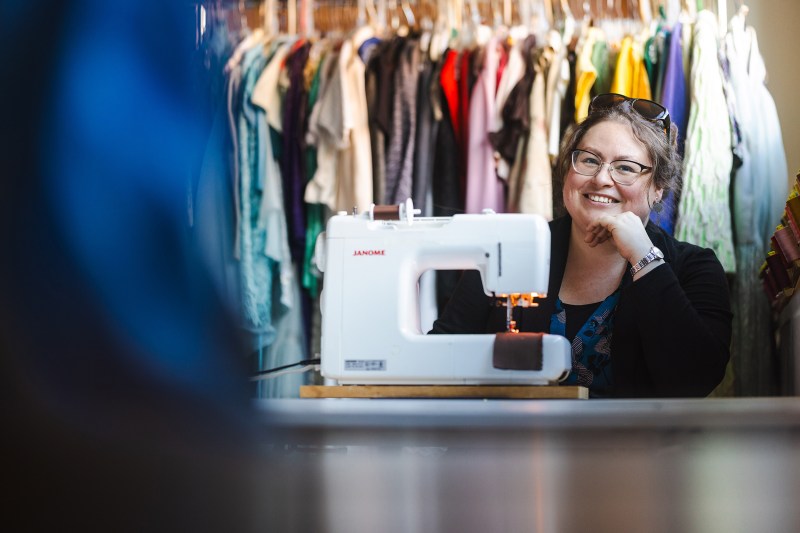 Olivia Trees sits behind her sewing machine and smiles at the camera
