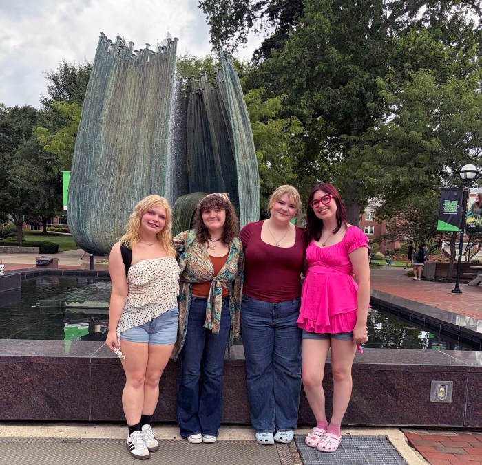 Payton and her friends smile together for a photo in front of Marshall University's Memorial Fountain