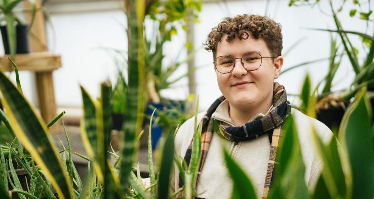 A student with plans in the Marshall University greenhouse on the Huntington campus