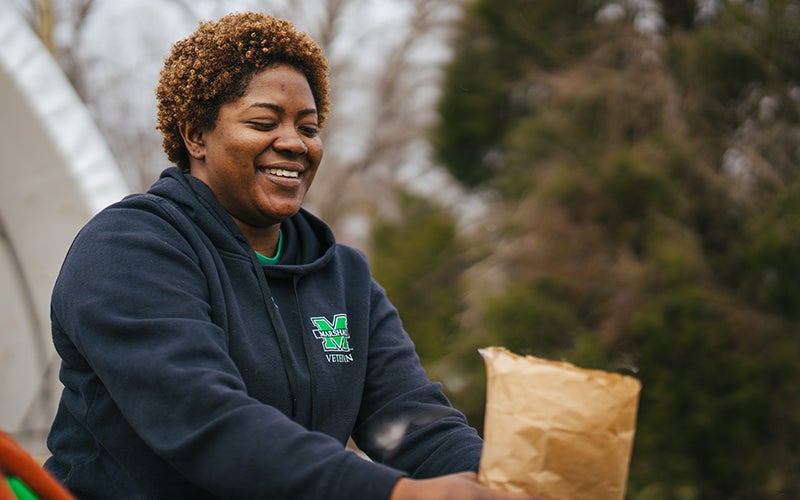 A staff member spreads compost