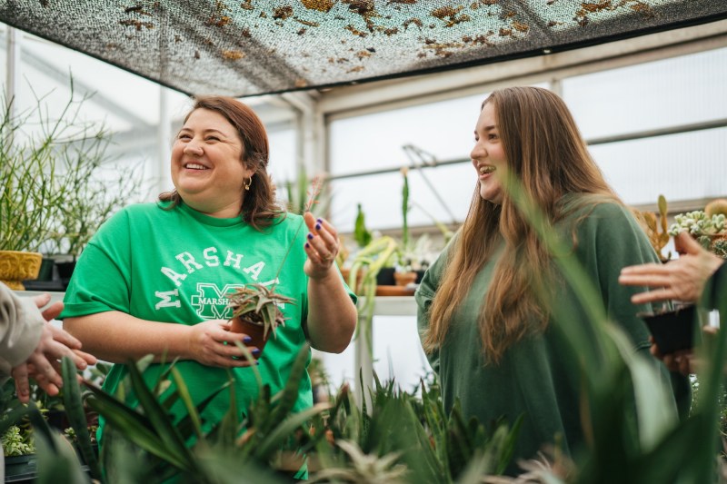 professor and student laughing in the greenhouse
