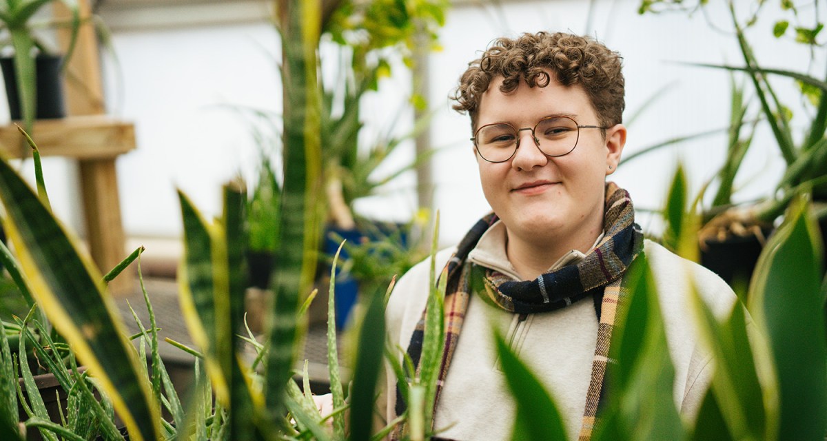 A student with plans in the Marshall University greenhouse on the Huntington campus