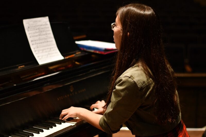 Image of a female student playing a piano.