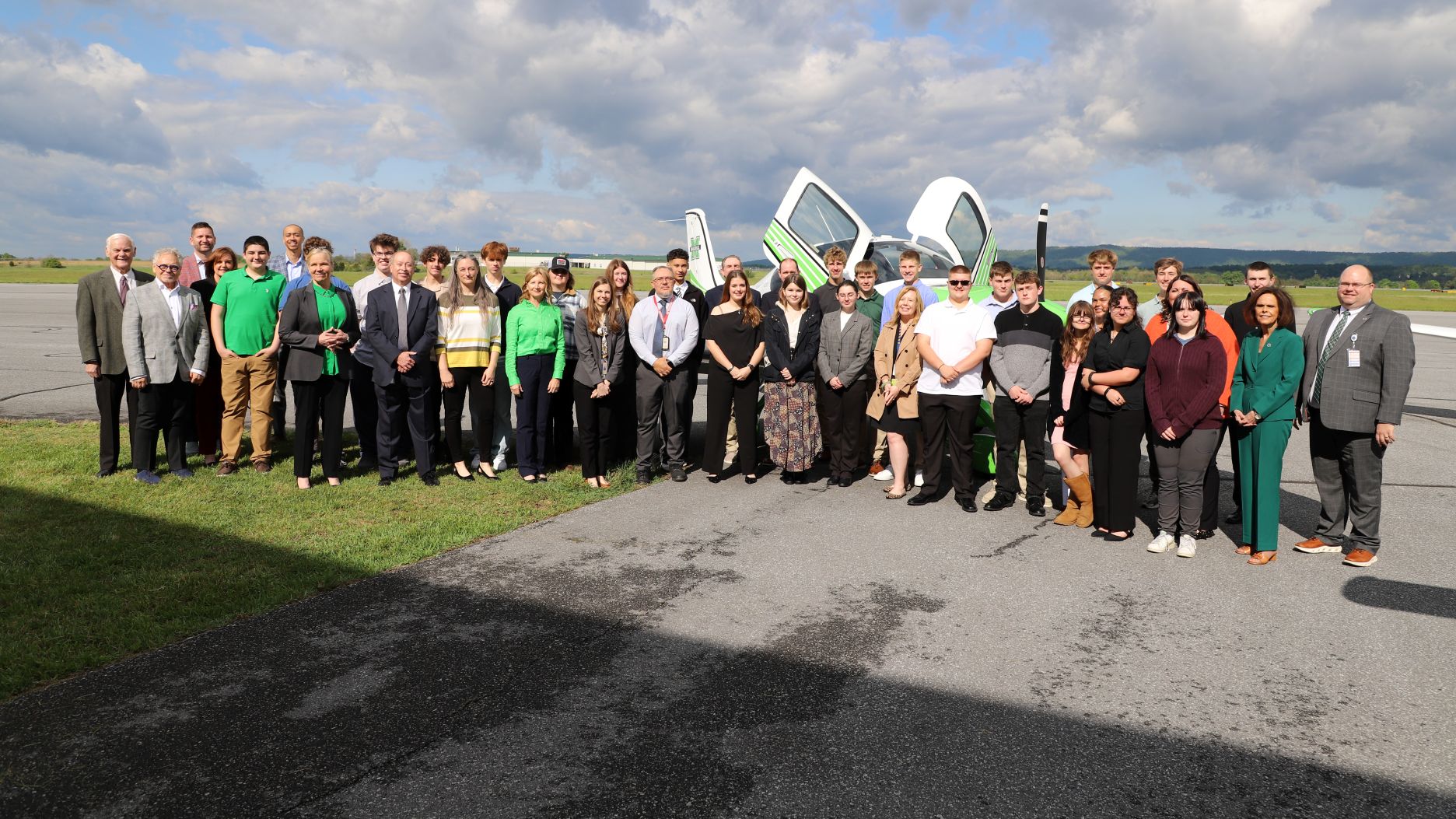 A group of Berkeley County high school students, administrators and Marshall University officials stand in front of an airplane.