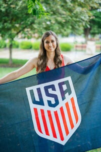 Skye Reymond holds a large US soccer flag in front of her