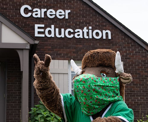 Masked Marco in front of Career Education building