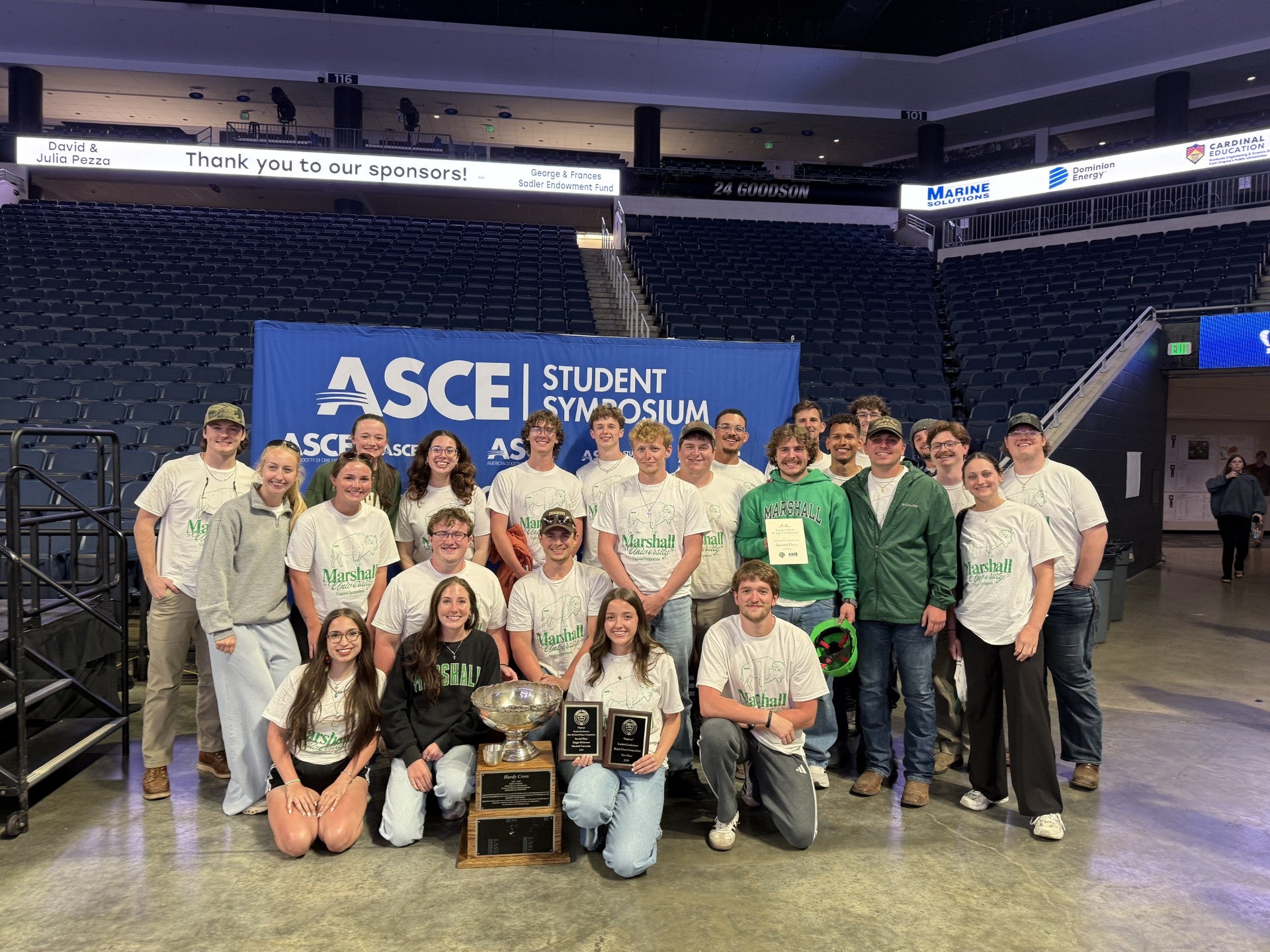 Group of twenty engineering students gather for a photo opp in a coliseum.