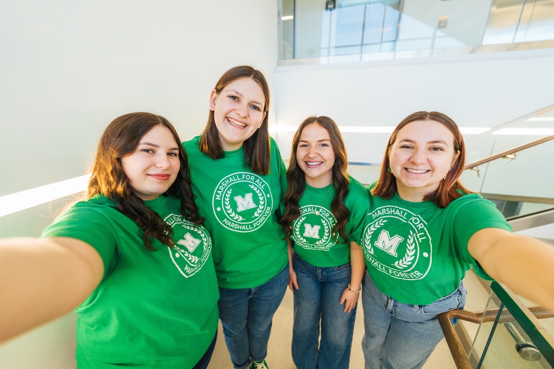 four Marshall for All students smiling at the camera in the College of Business building