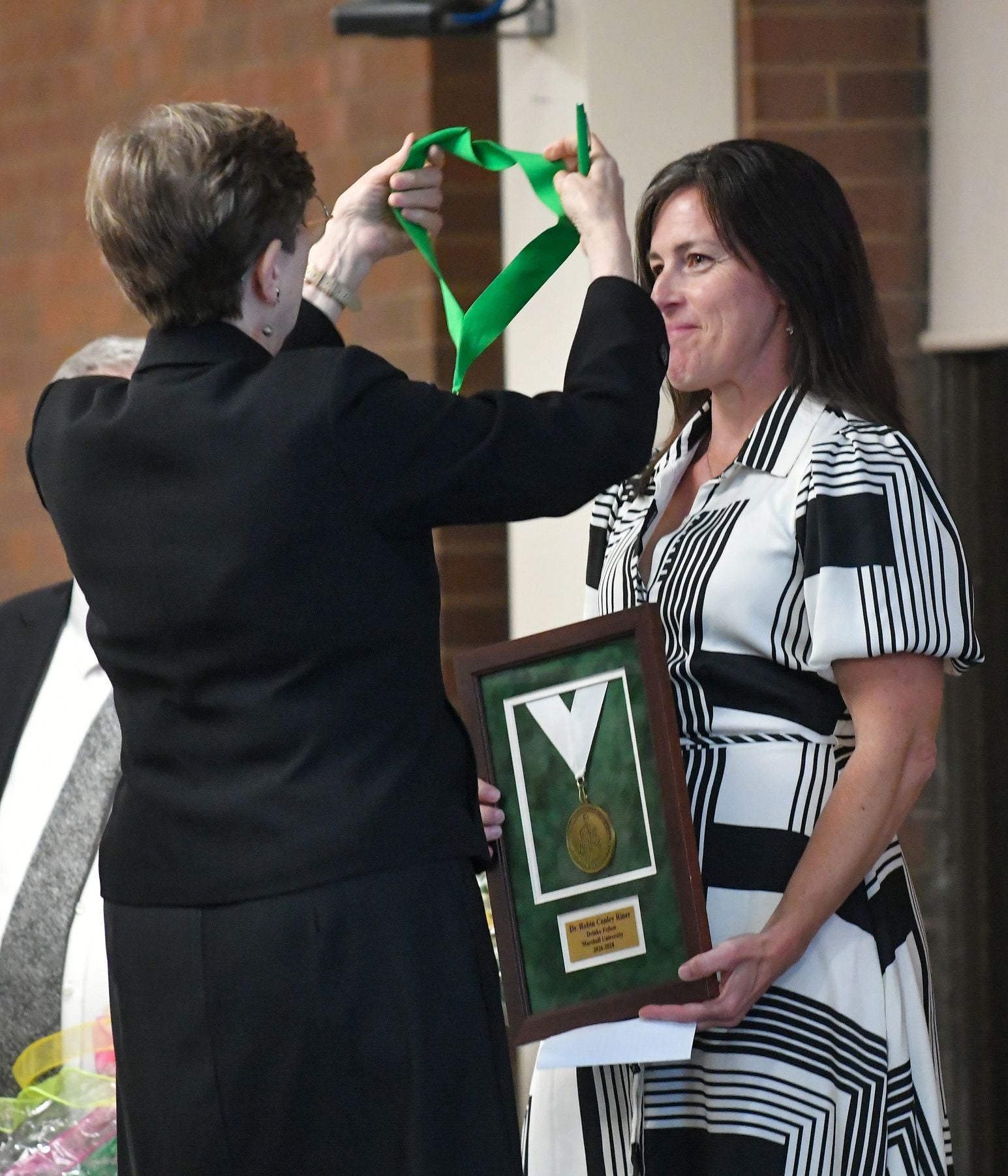 Female placing medal over another female.
