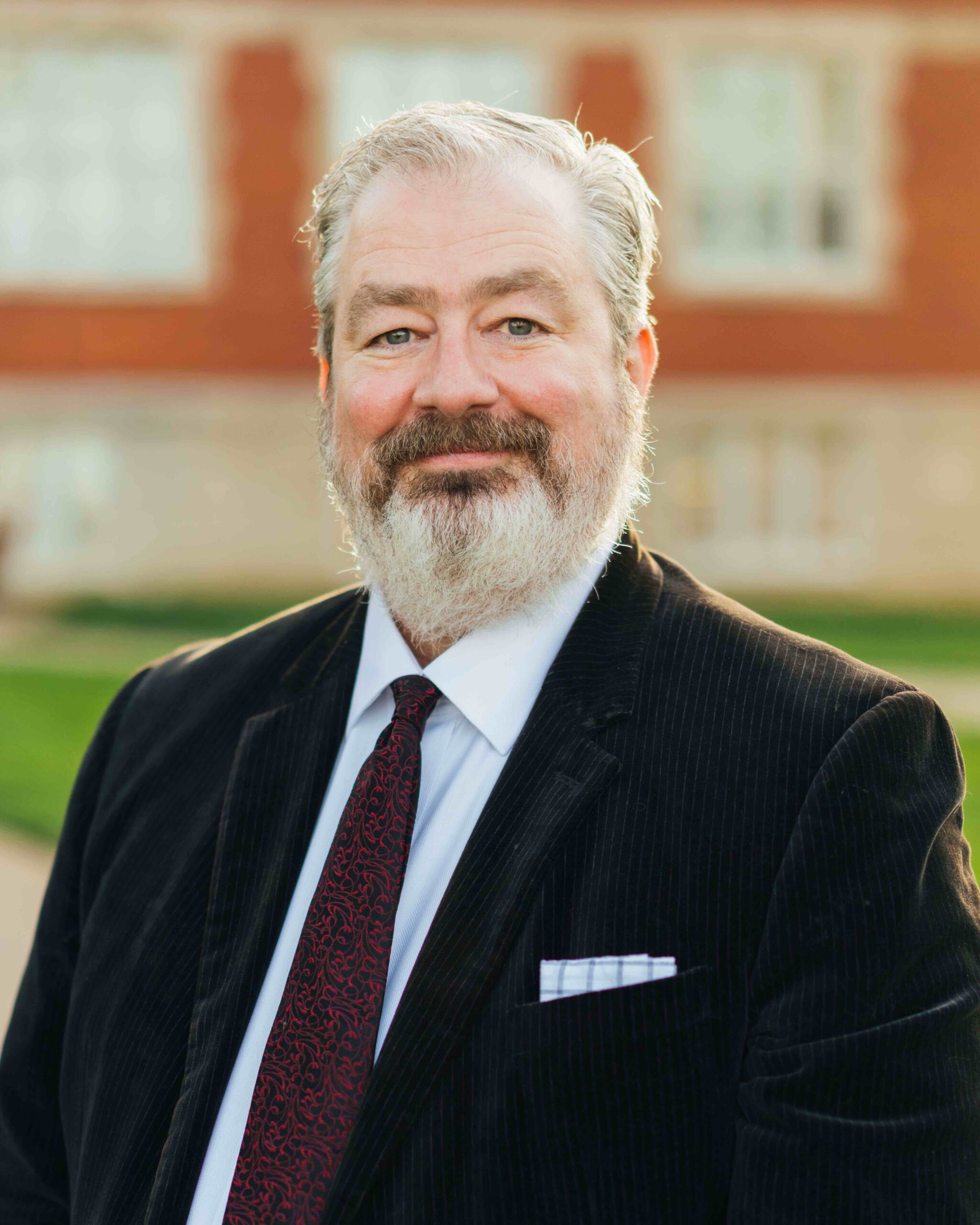 Man with beard and mustache and wearing a dark suit.