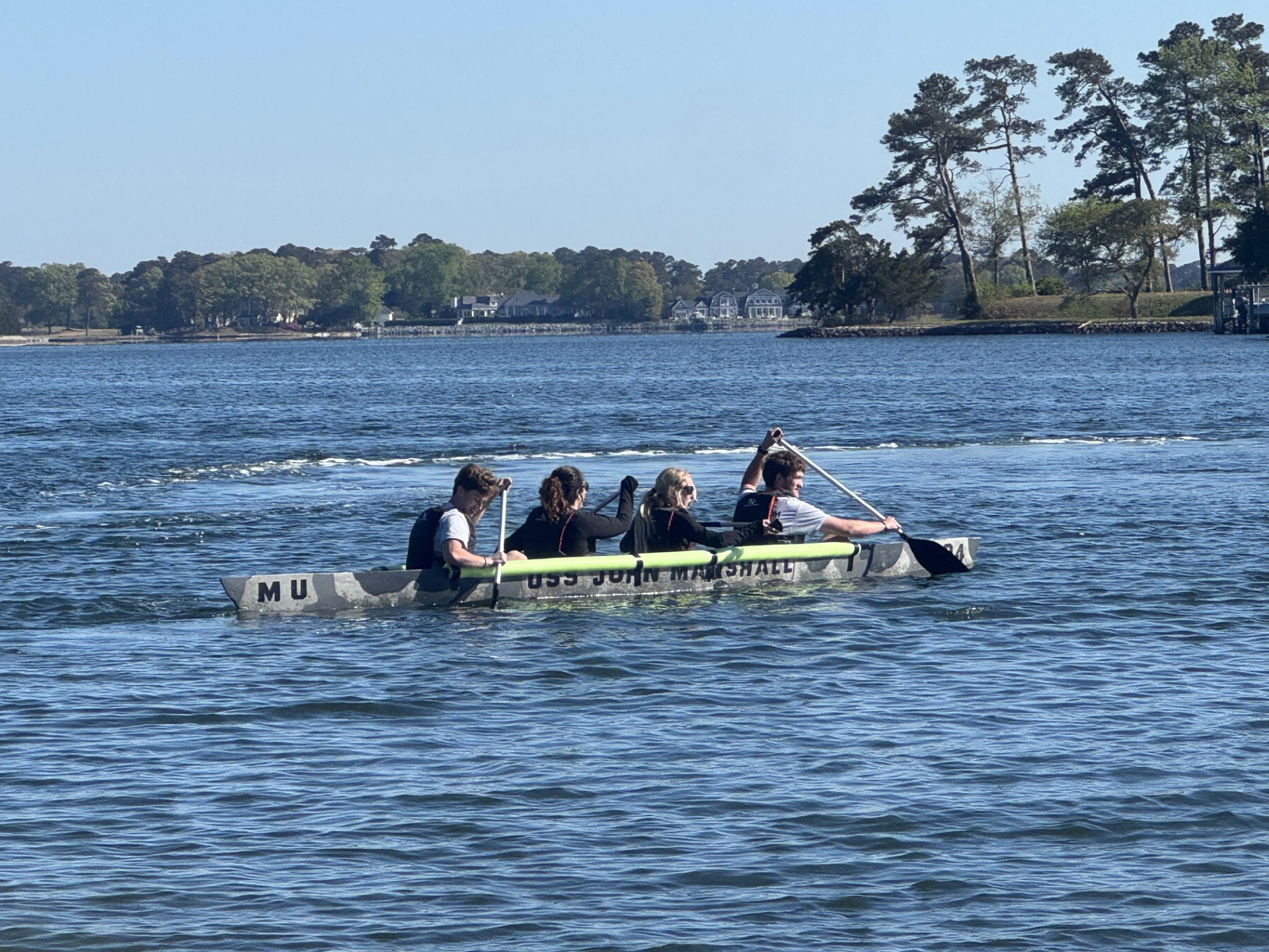Four students in a concrete canoe on a lake.