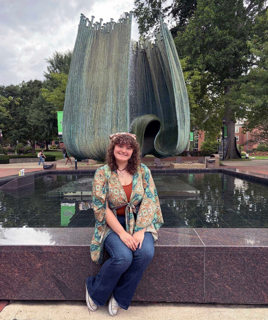 Payton Austin sits in front of the Memorial Fountain at Marshall University