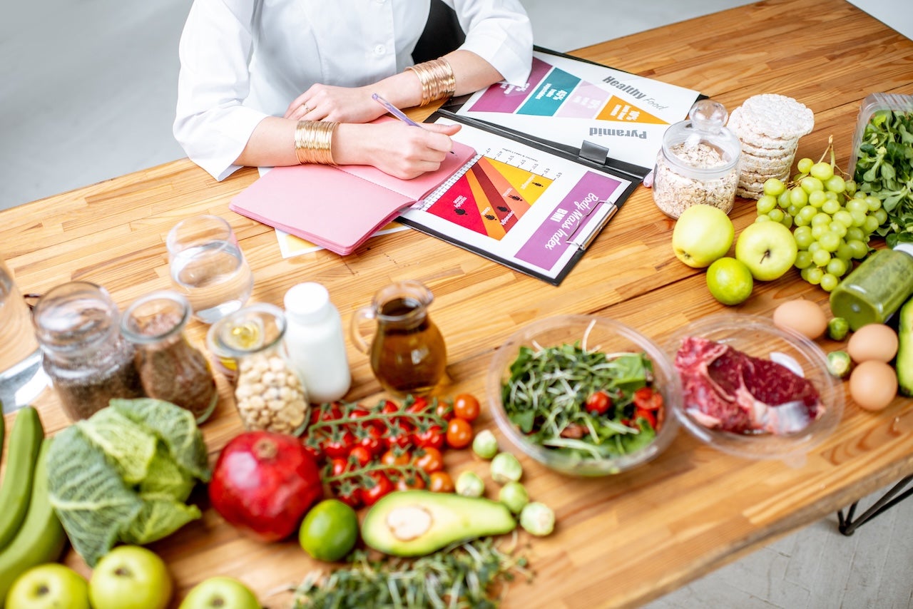 Image of female writing with food surrounding her on table