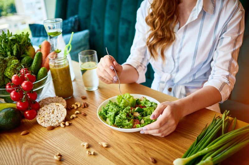 Image of Young happy woman eating salad