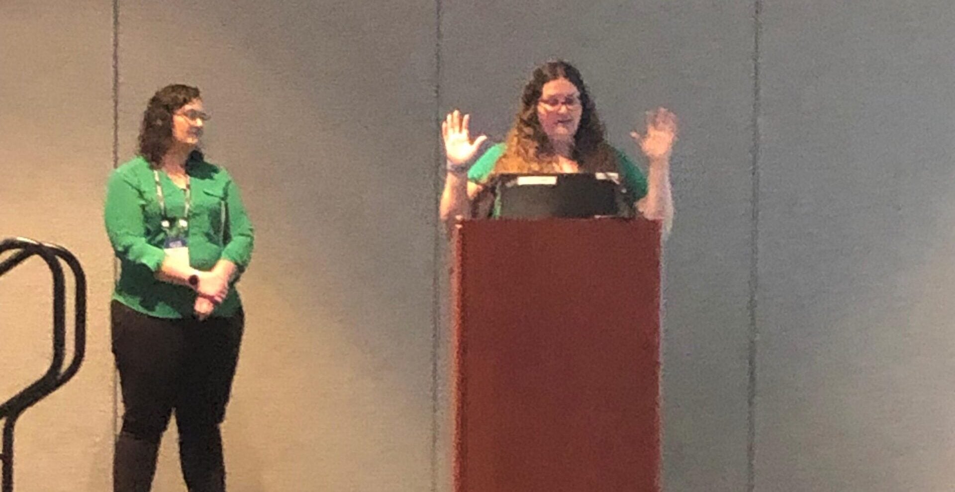 woman presenting at podium with co-presenter next to her