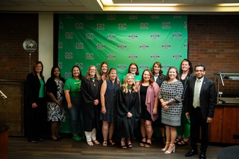 student with family and friend support at Marshall Online graduation reception