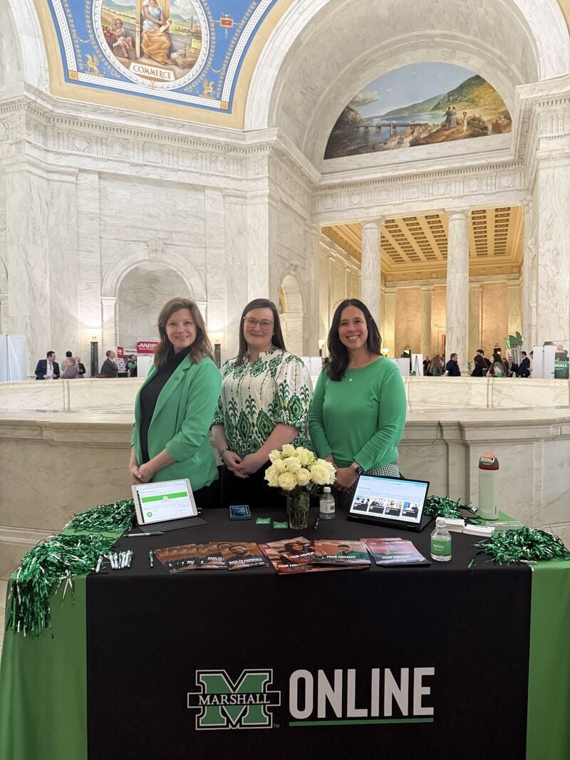 three women posing behind a table that says Marshall Online