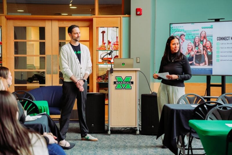Two presenters lead a session beside a Marshall-branded podium, with a 