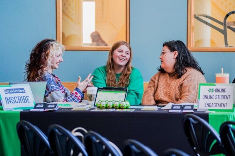 Four panelists talk and smile at a table marked with 