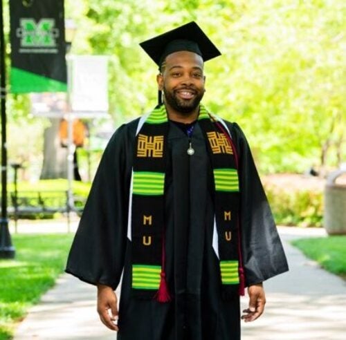 A Student standing in their cap and gown.