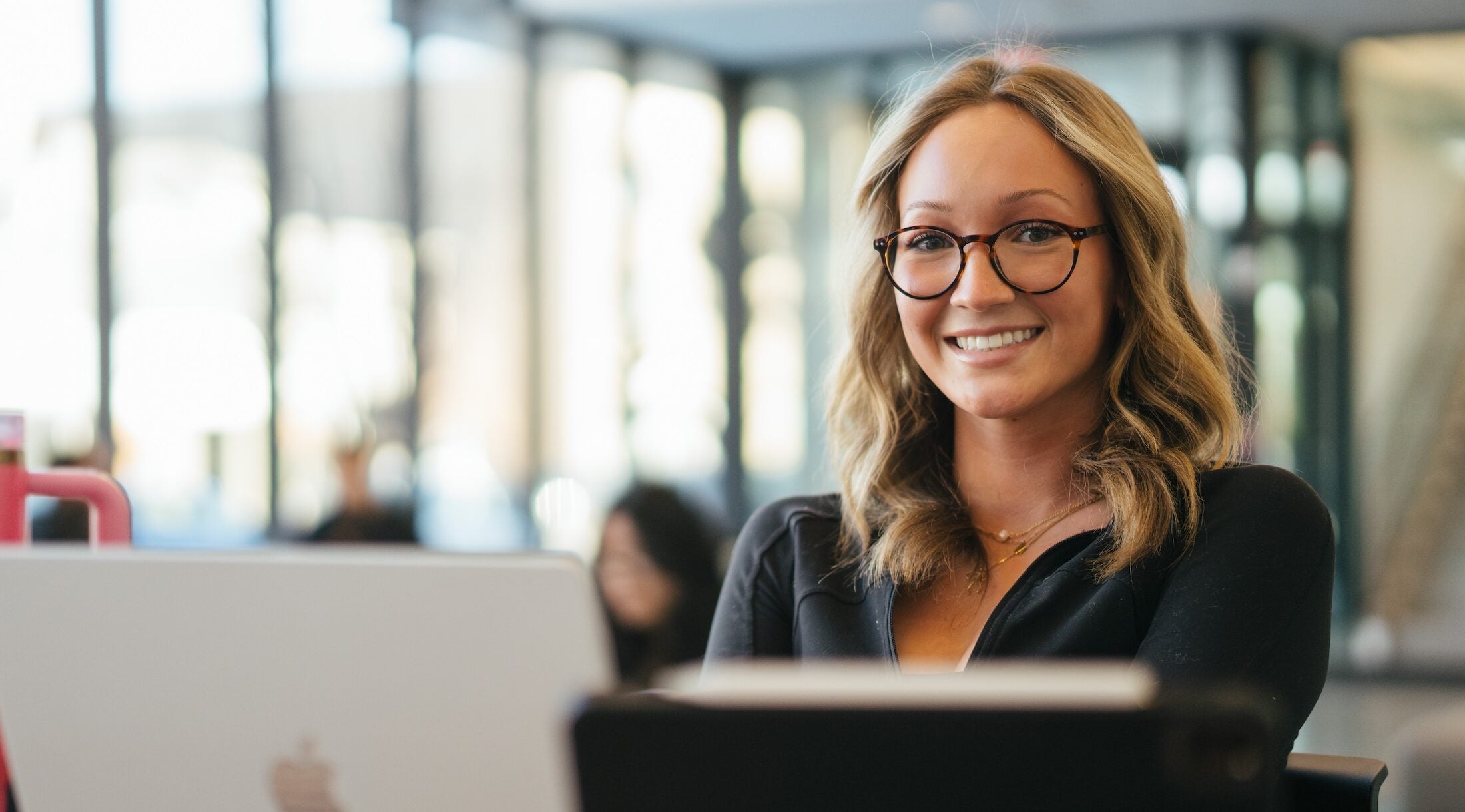 student working on a laptop and smiling at the camera
