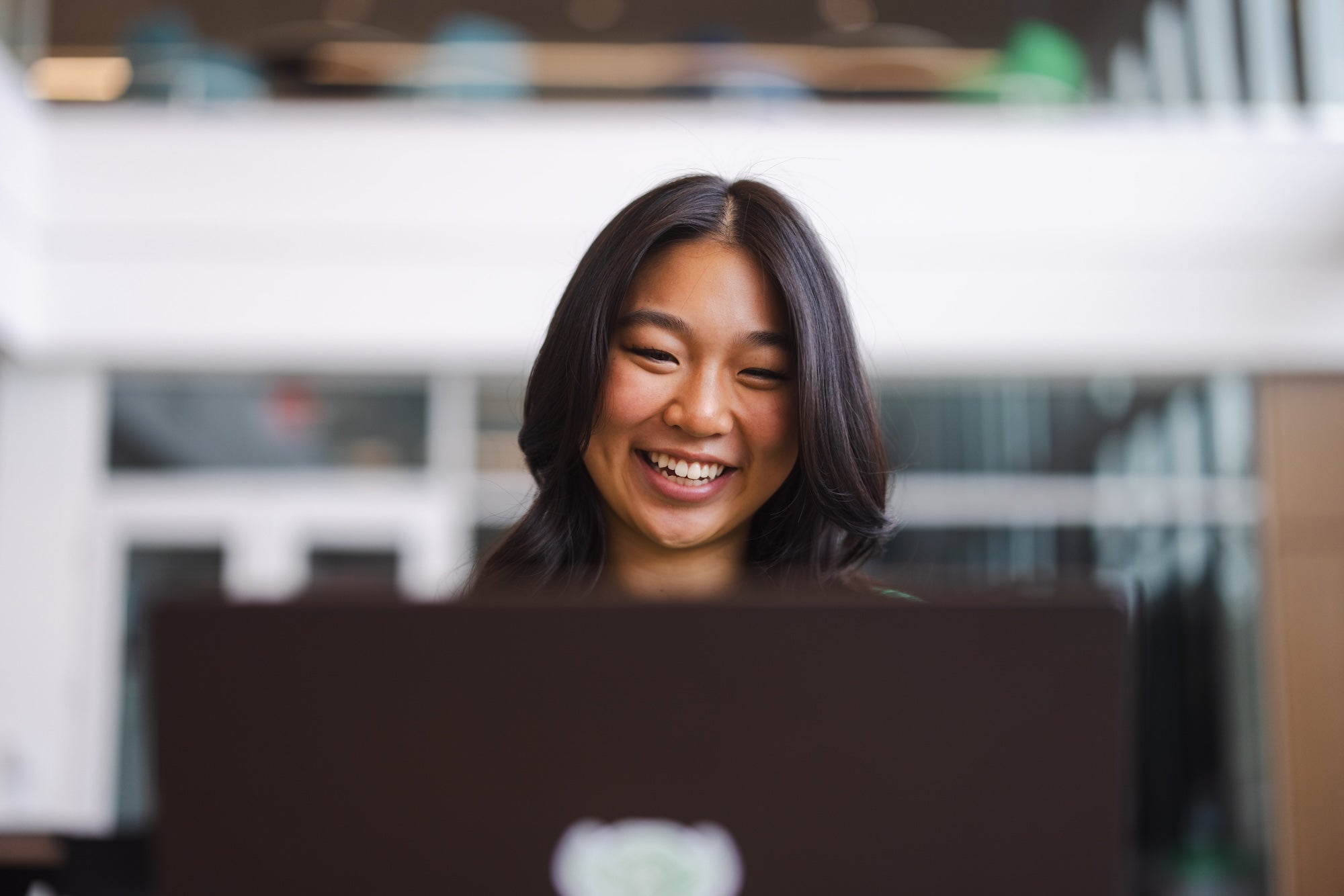 student working on a laptop and smiling at it