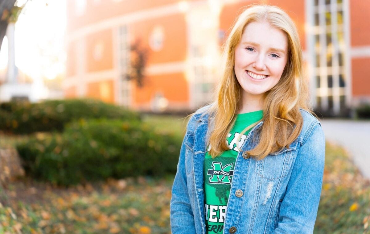 Student smiles in front of the library on Marshall University's Huntington campus