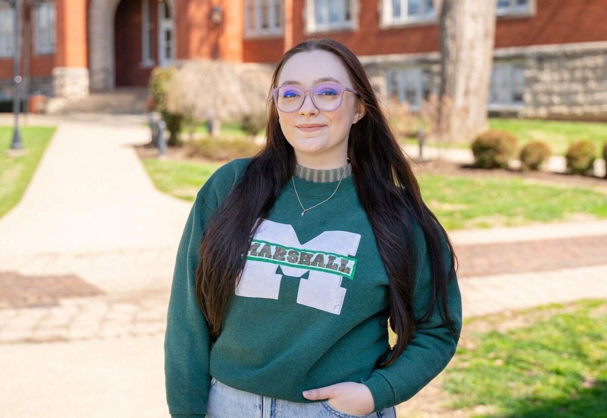 Student smiling at the camera in a Marshall sweater