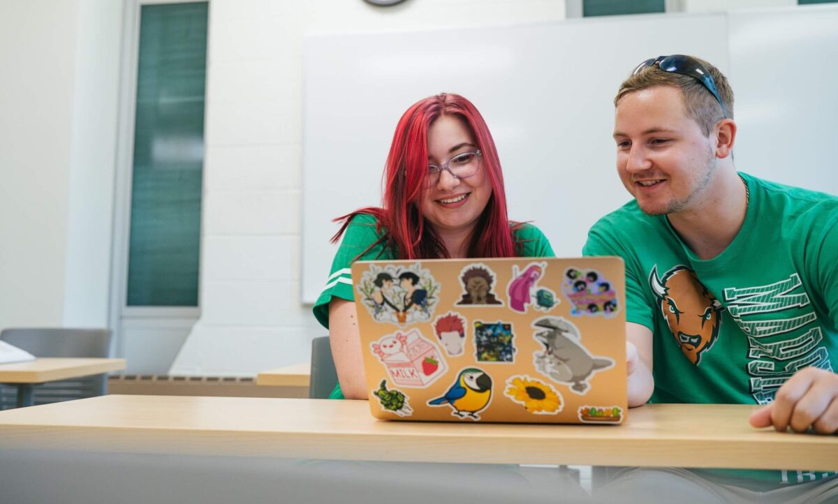two students working on a laptop