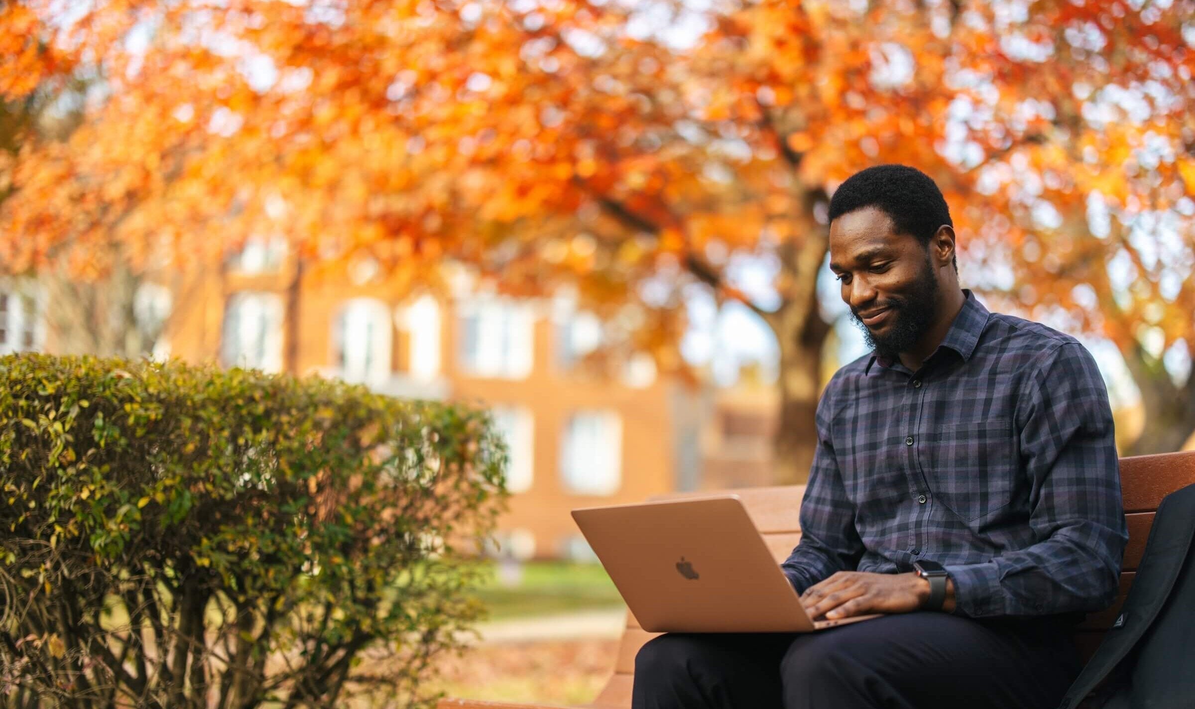 student working outside on a laptop during the fall