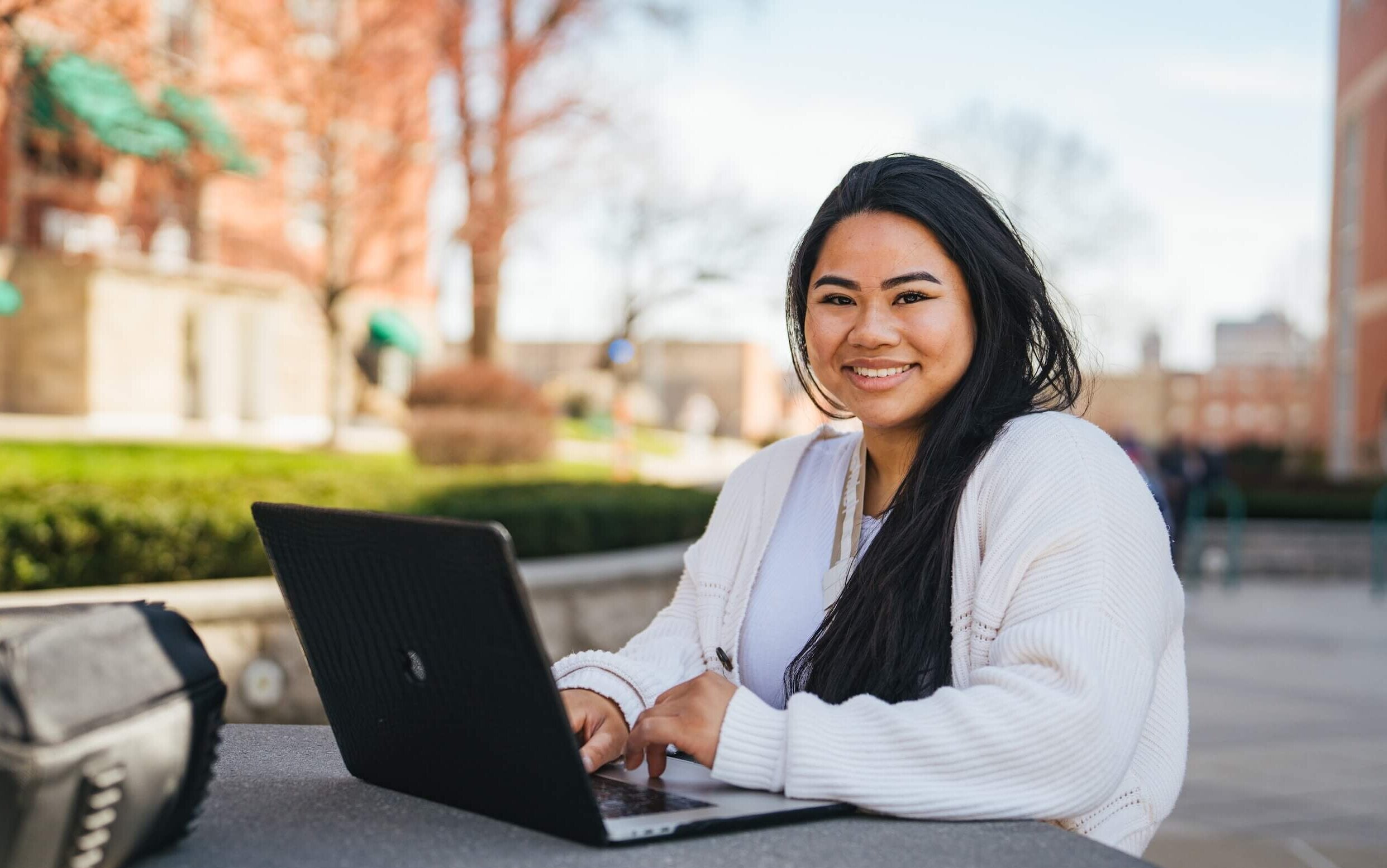 student sitting at a laptop outside
