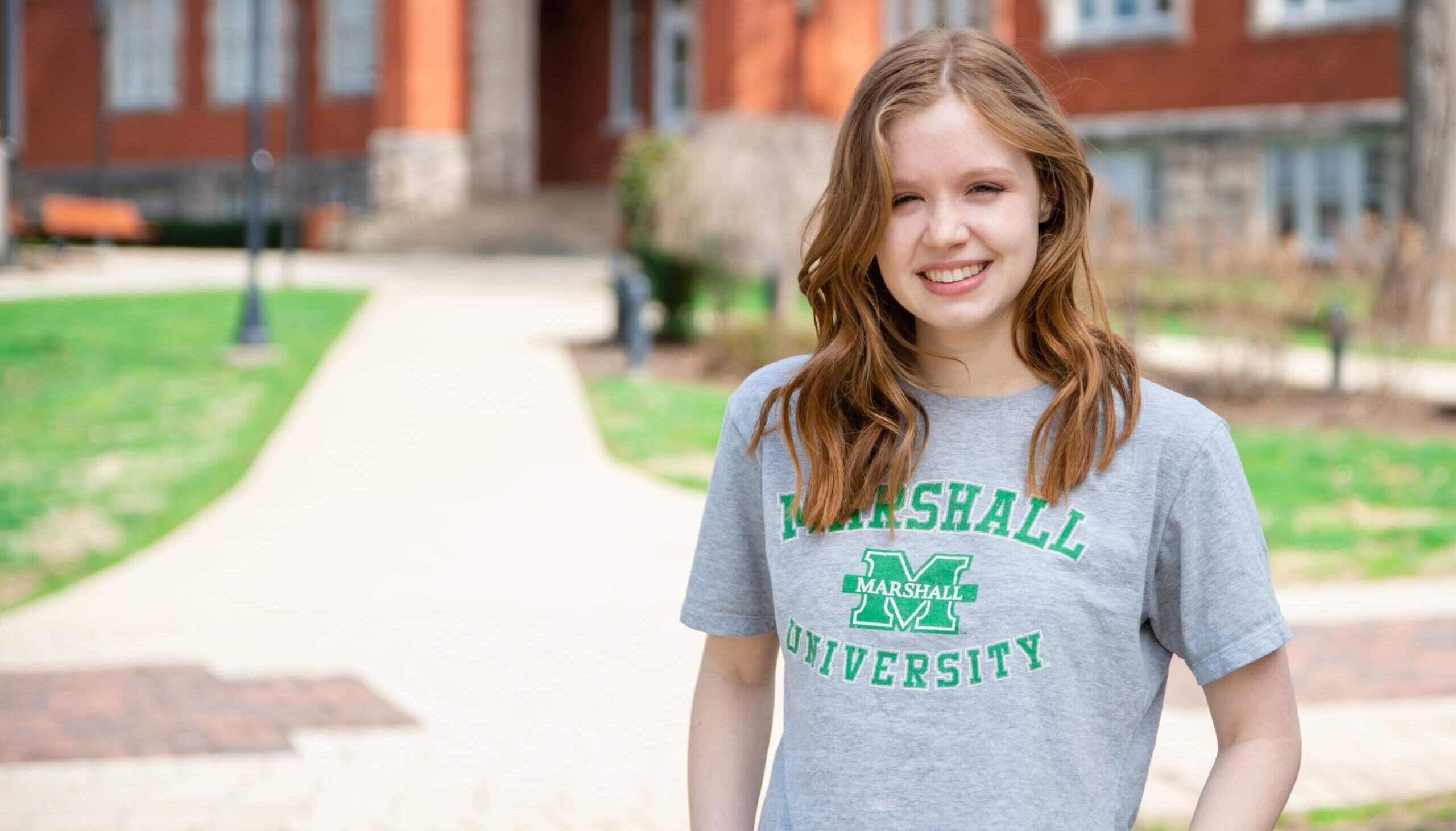 student smiling at the camera in front of Old Main