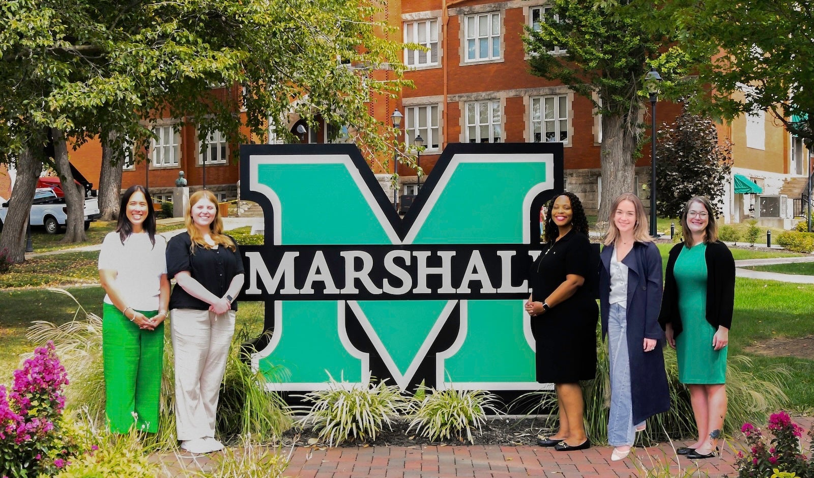 five members of the Student Engagement Team posed by the block M on Old Main and smiling at the camera