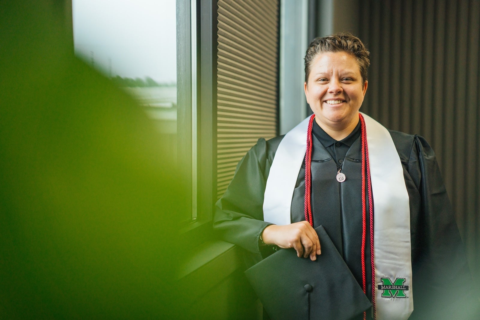 Alexie Adkins smiling at camera in graduation gown