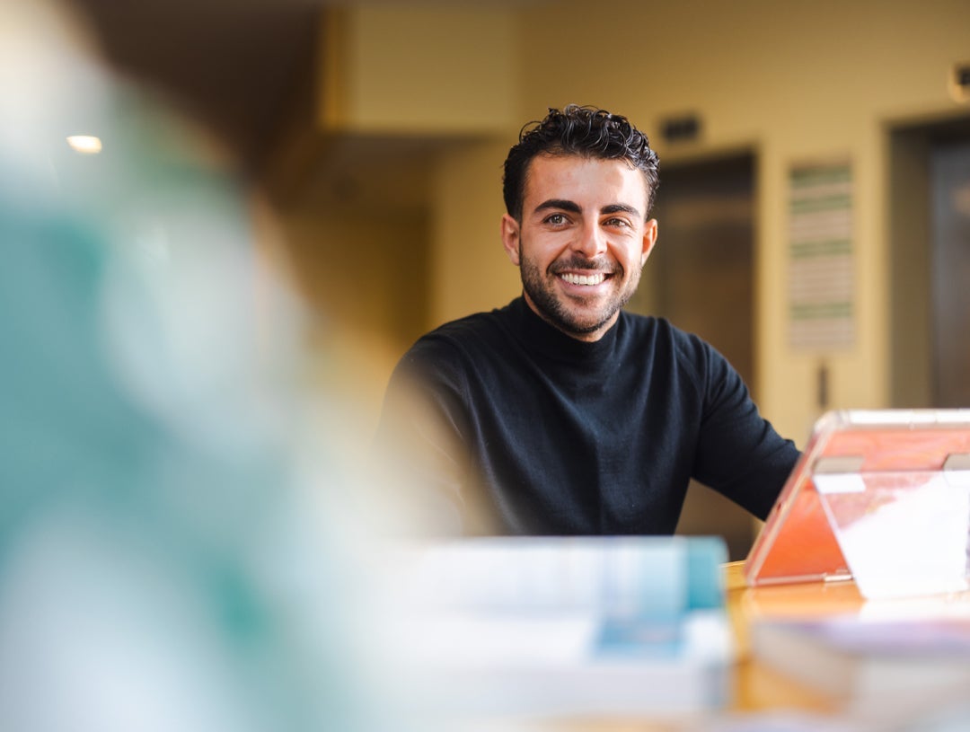 Student smiles at someone while studying on an iPad.
