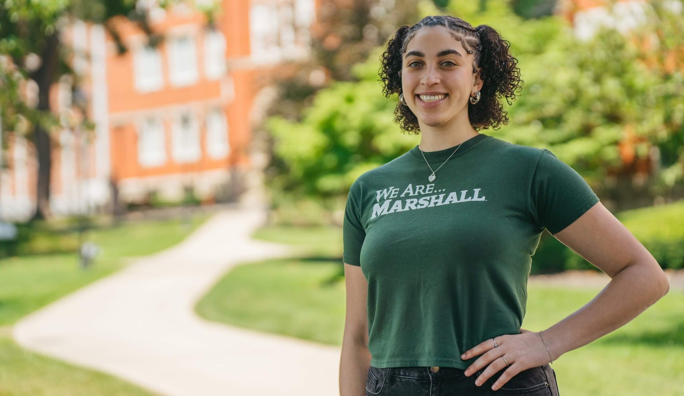 student standing in front of Old Main smiling