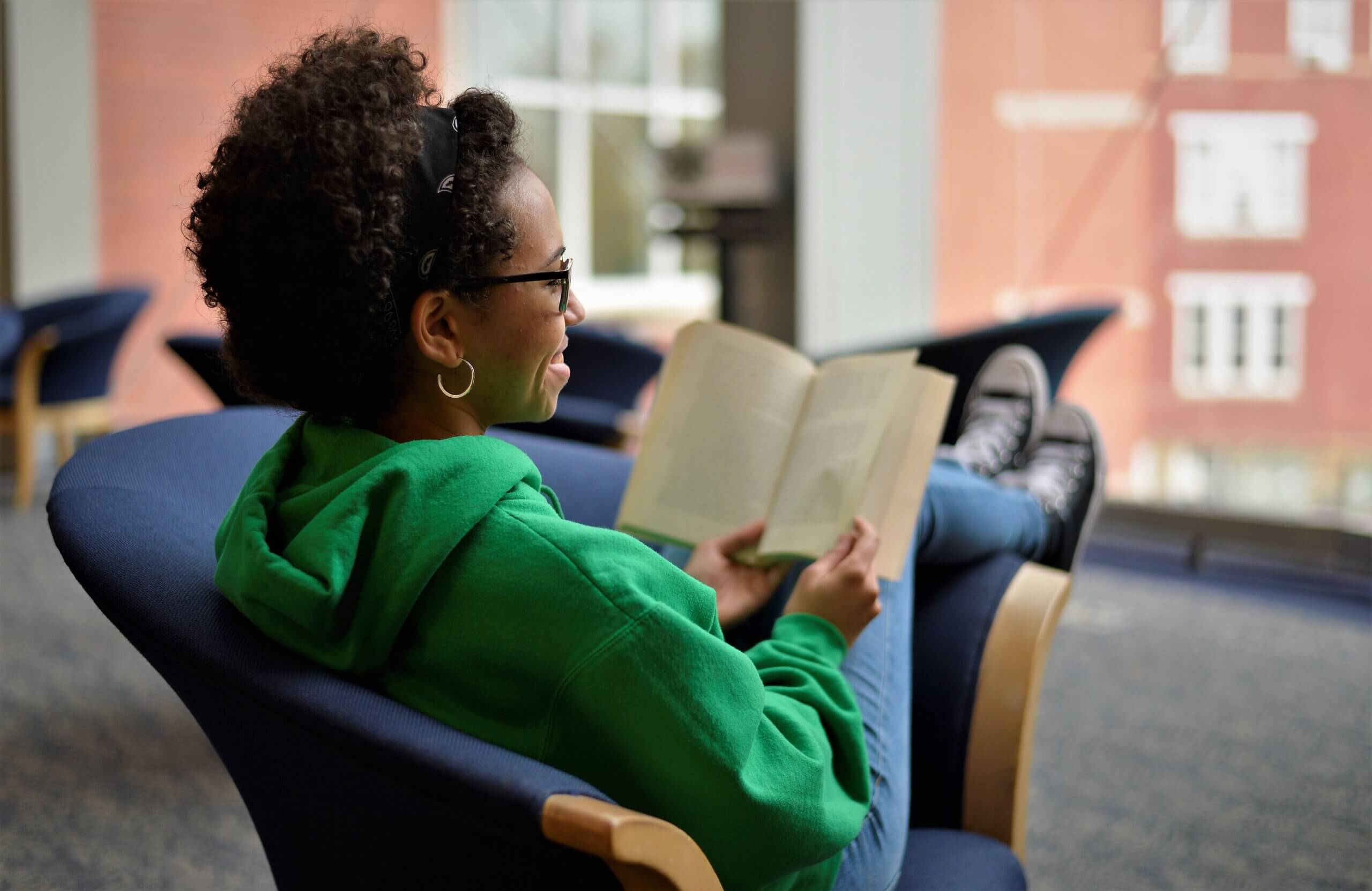 student reading a book with feet propped up