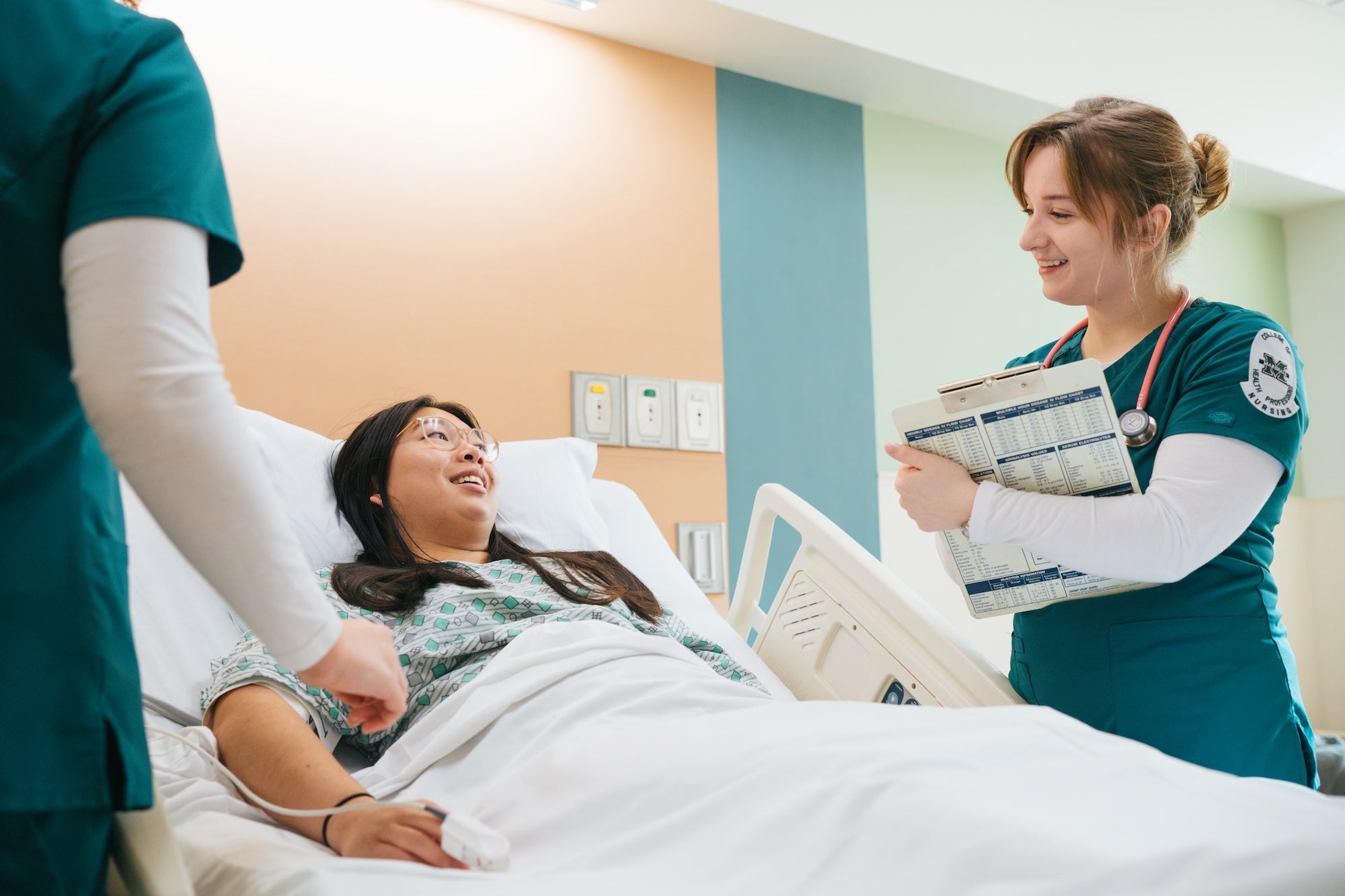 two nurses taking care of a patient in a bed