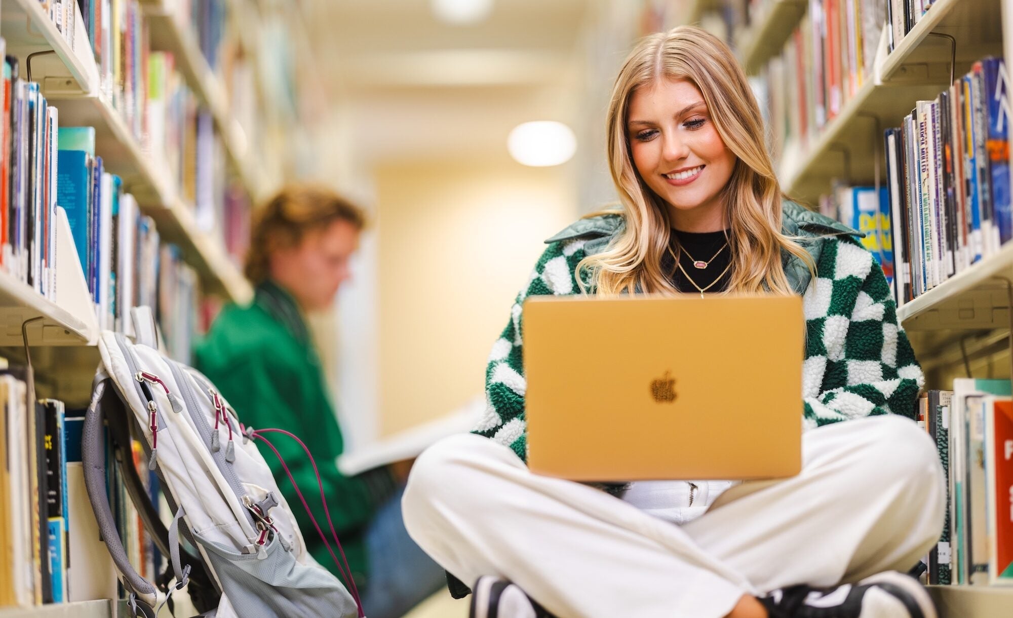 student athletes working on laptops in the library