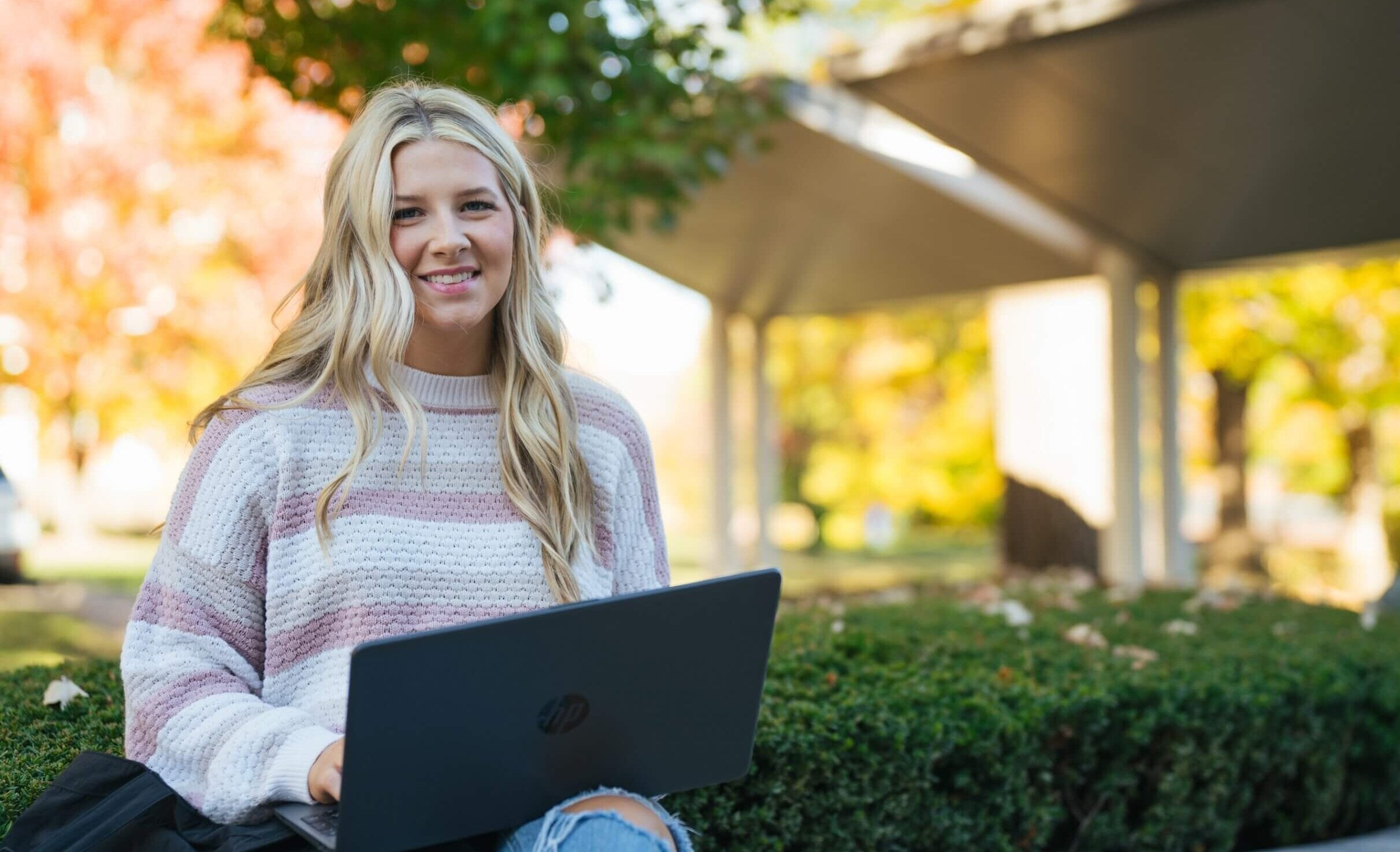 student working on a laptop outside and smiling