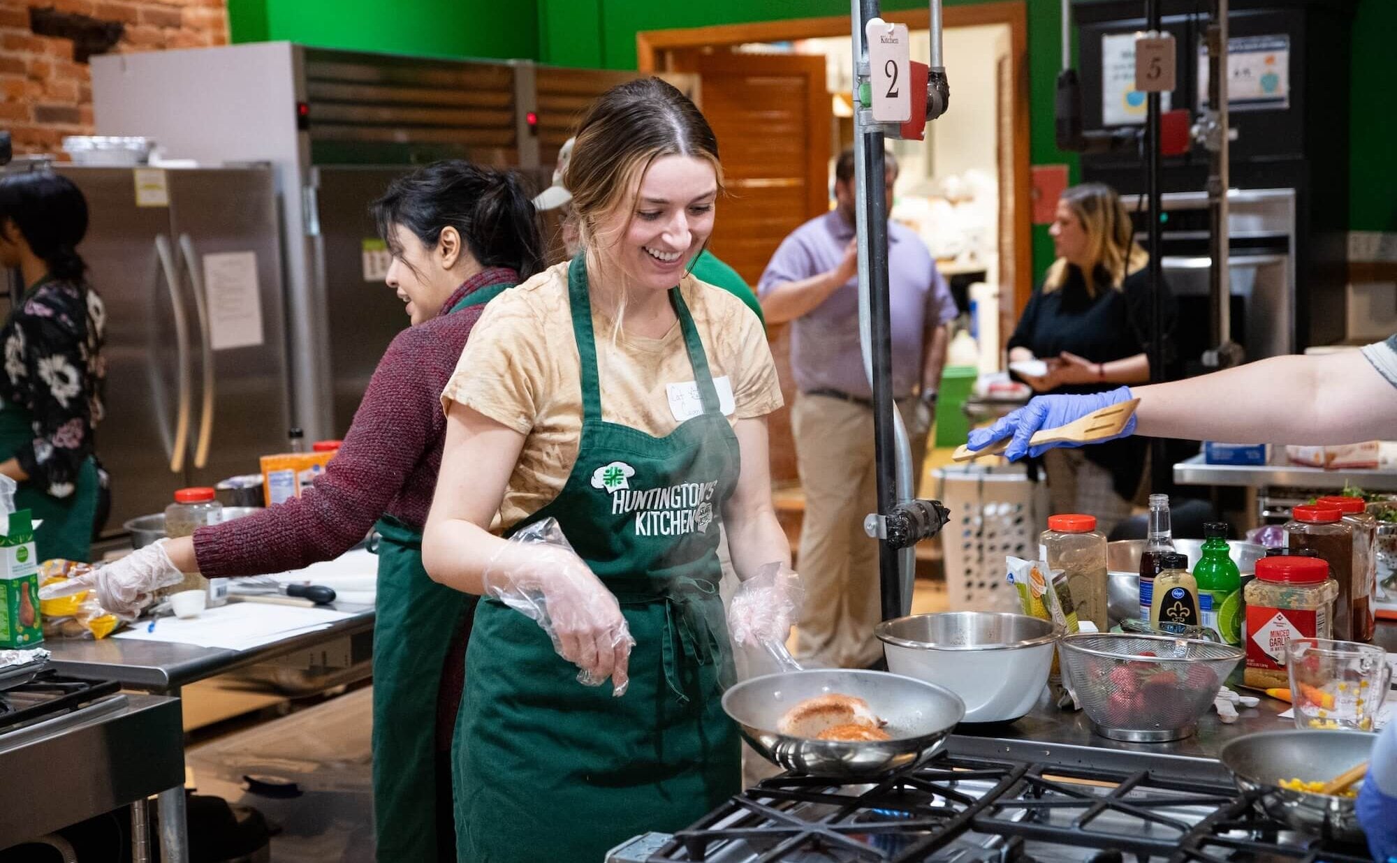 student cooking in a pan on a stove at Huntington's Kitchen