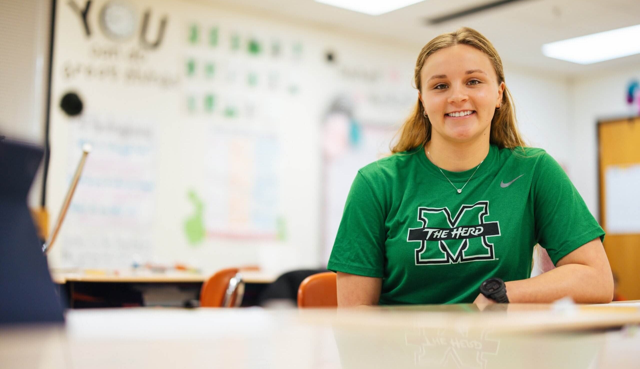 teacher in an elementary school classroom smiling at the camera