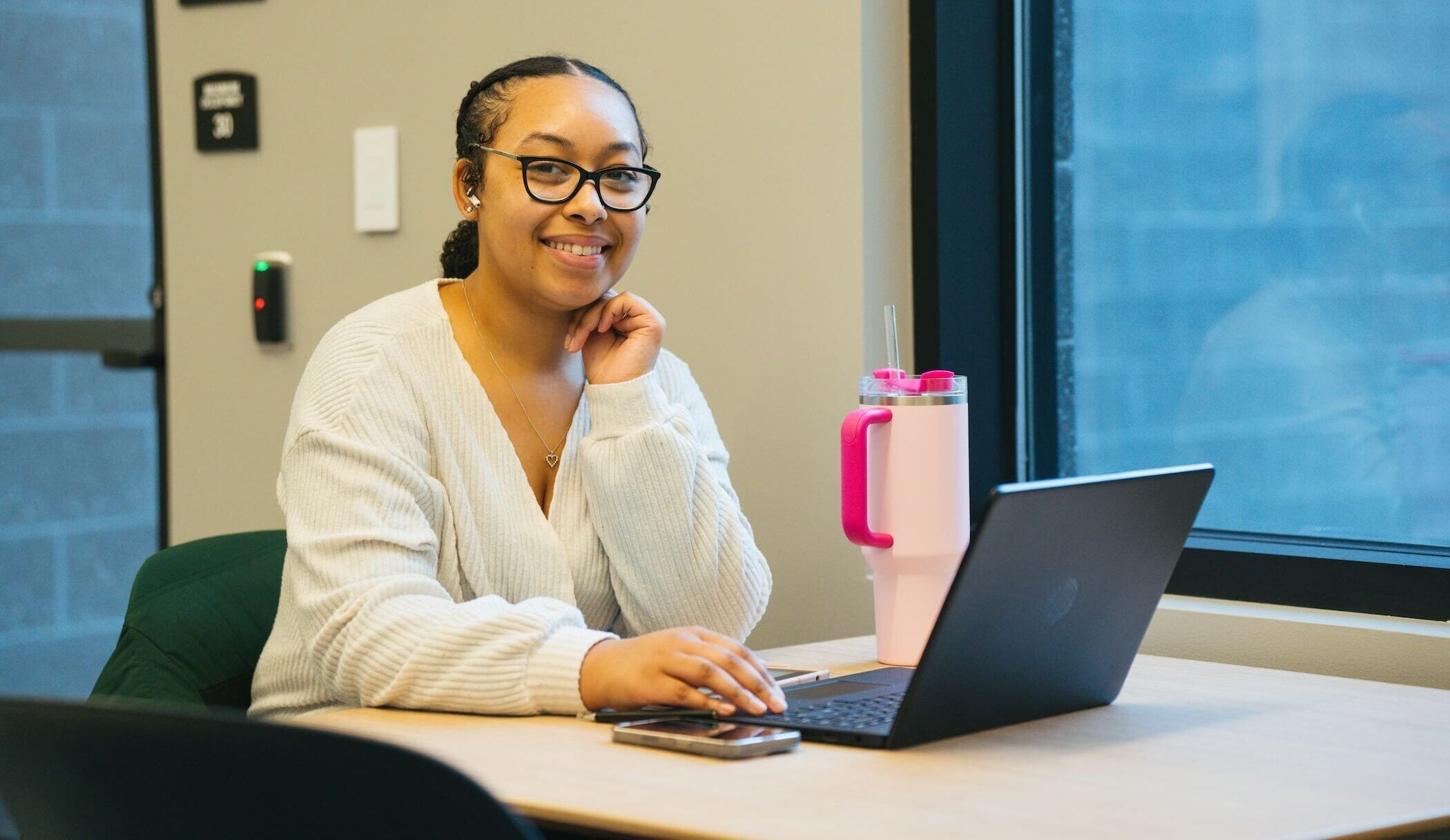 student working on a laptop and smiling at the camera
