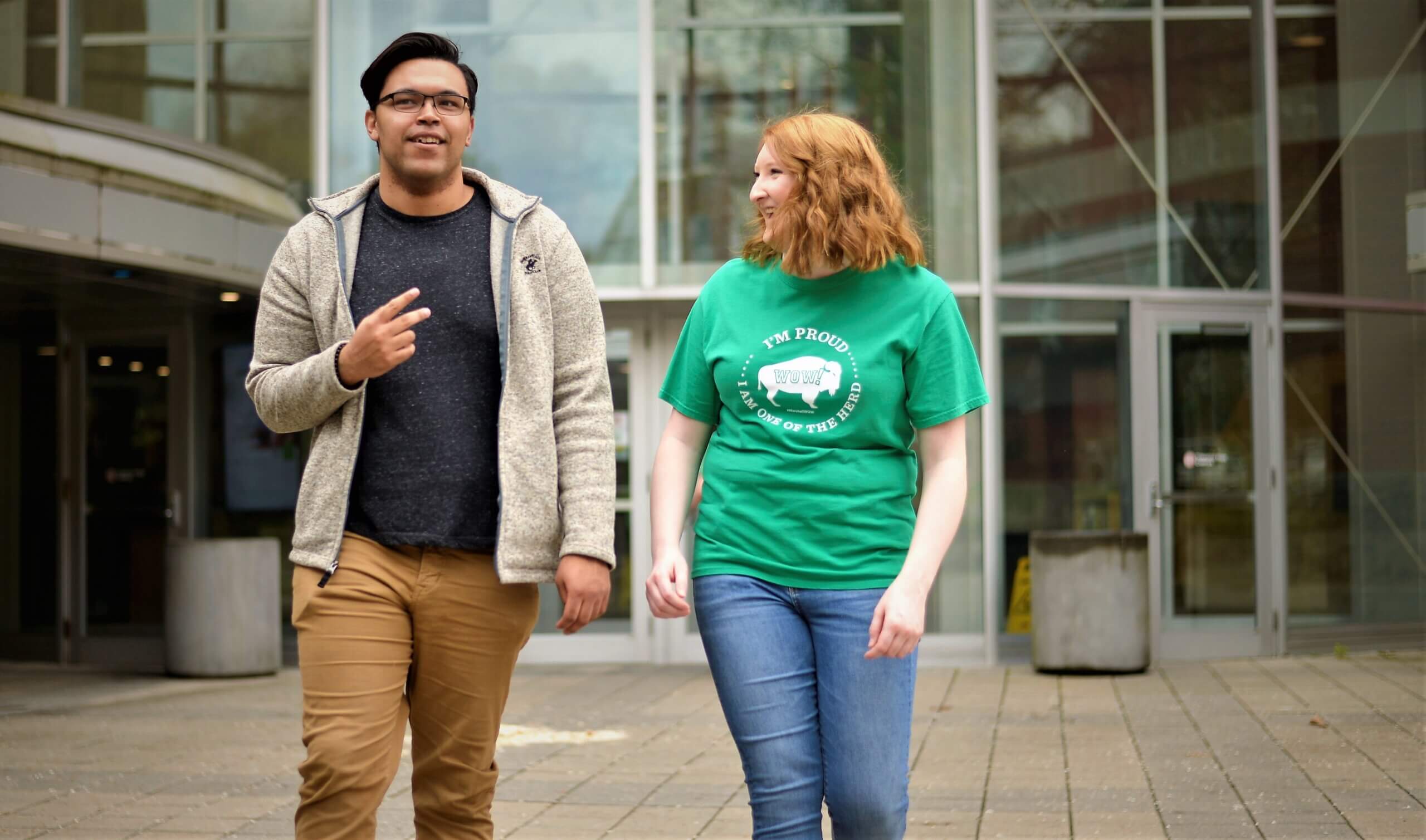 Two students walking together in front of the library at Marshall University
