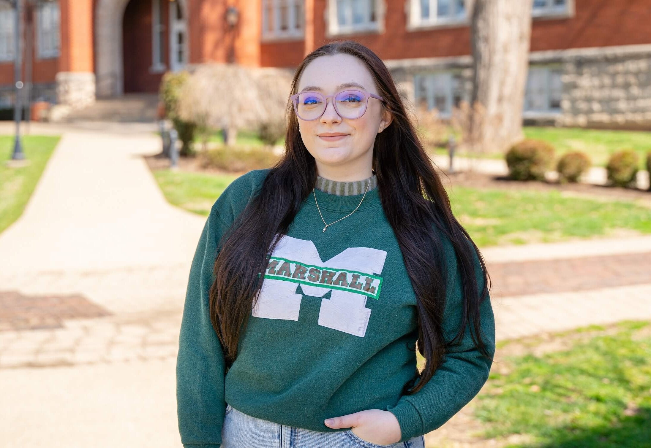 Student smiling at the camera in a Marshall sweater