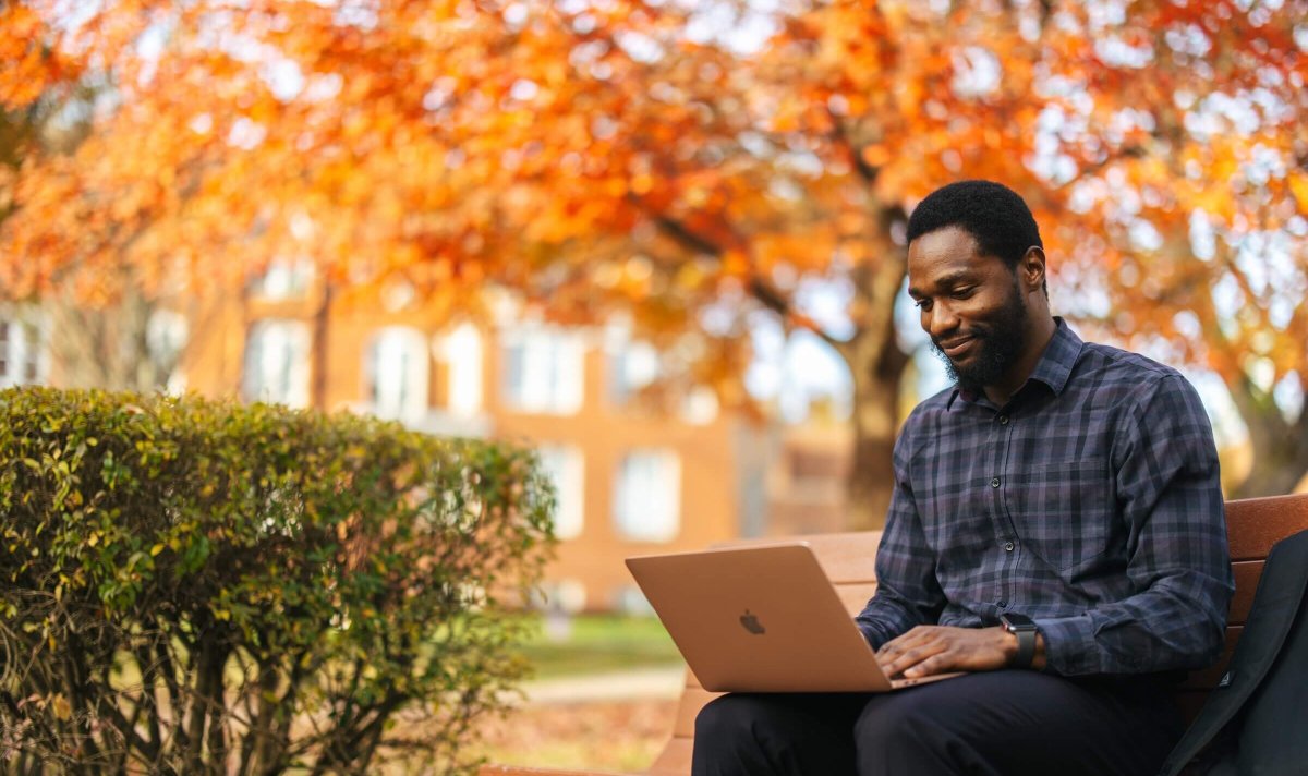 student working outside on a laptop during the fall