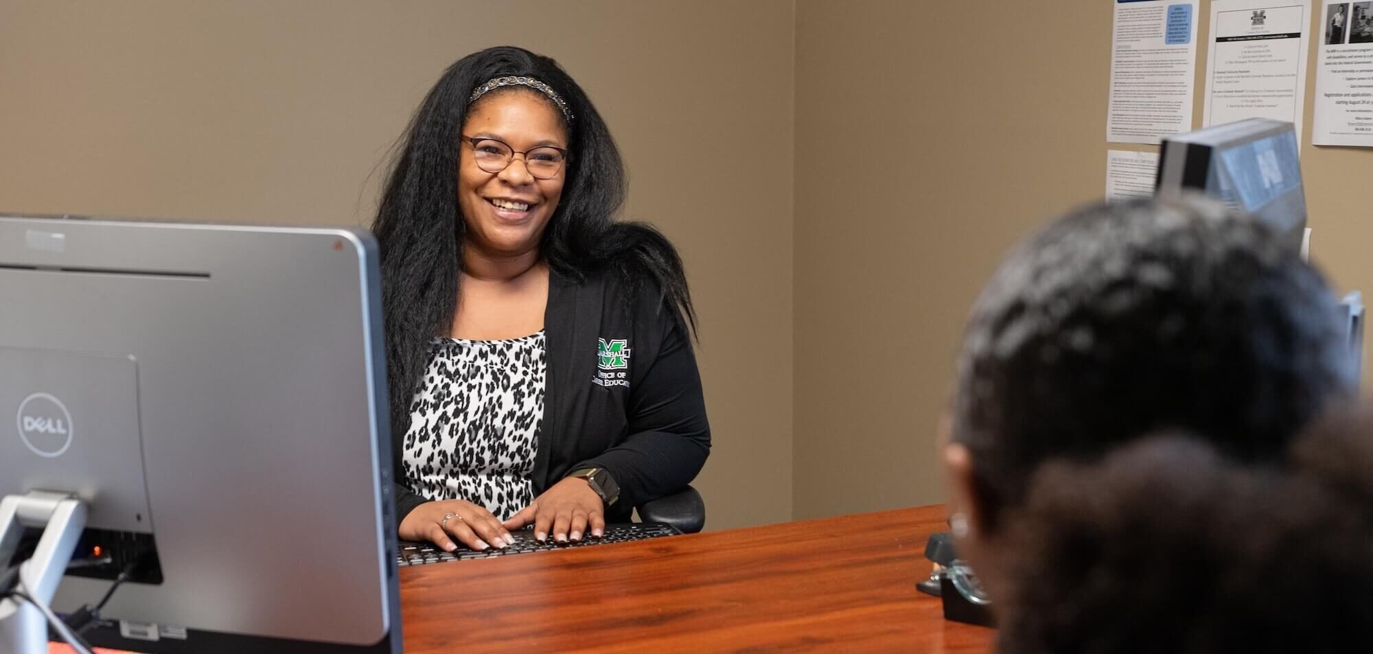 student talking across a desk to an employee