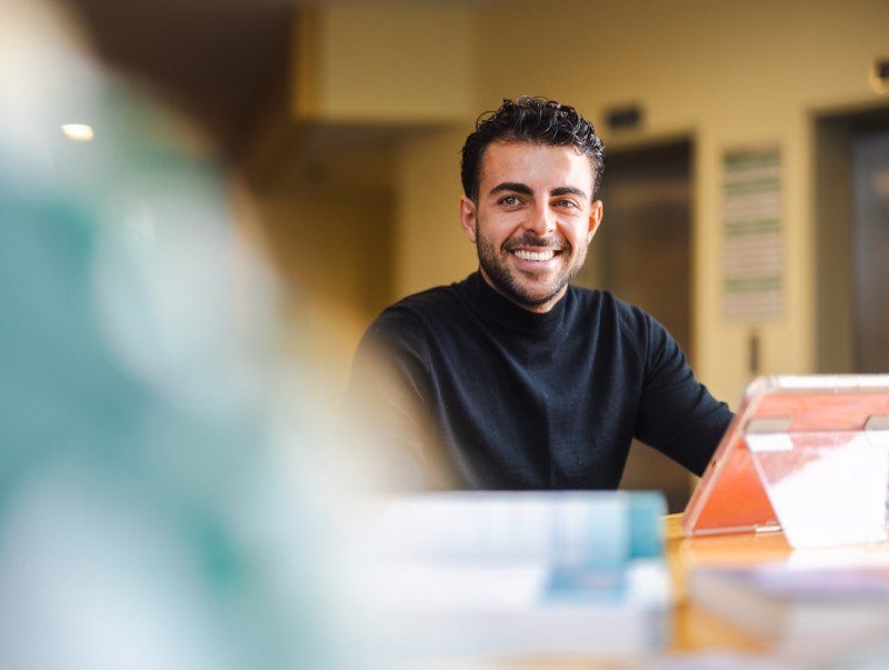 Student smiles at someone while studying on an iPad.